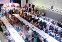 Widok z góry na salę zastawioną długimi stołami, przy nich siedzą ludzie